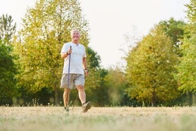 älterer Mann geht im Grünen walken um Bluthochdruck zu senken